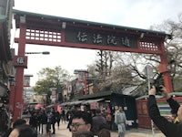 a group of people standing in front of a red torii gate