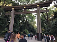 a group of people standing in front of a large tori gate