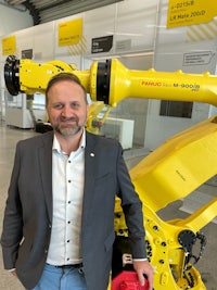 a man in a suit standing next to a yellow robot