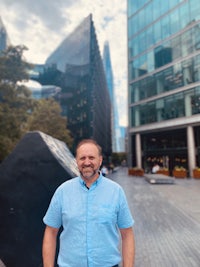 a man in a blue shirt standing in front of tall buildings